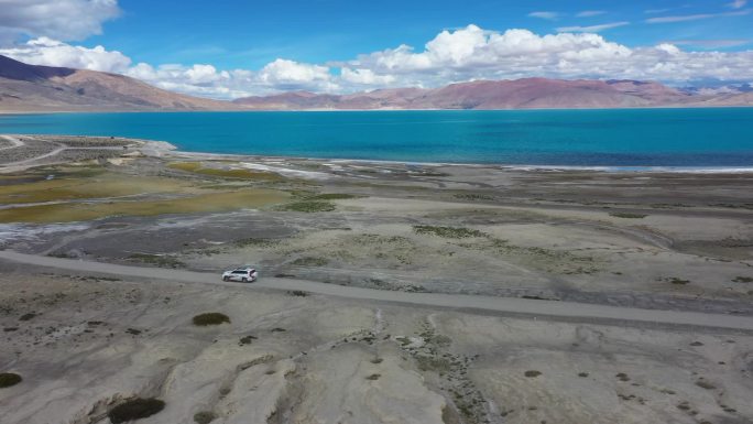 航拍越野车行驶在佩枯错湖边的土路上