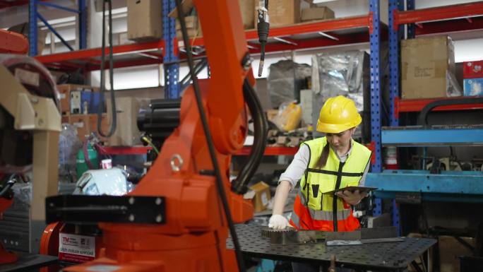 员工们在工厂里用机器人手臂工作。