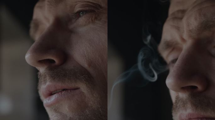一个阴郁的男人在窗户附近吸烟的肖像