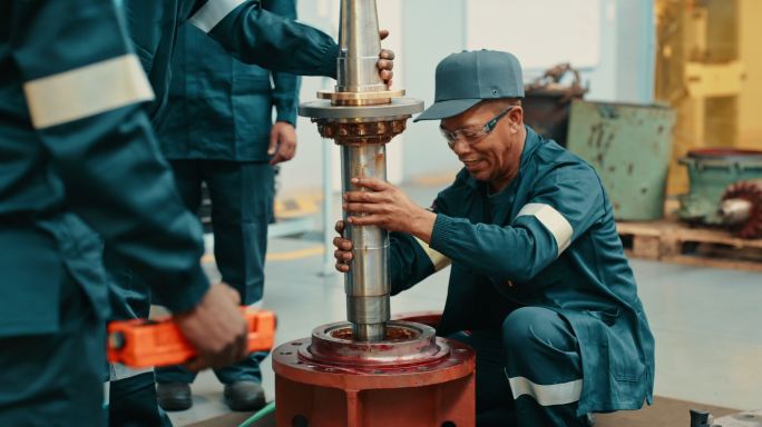 石油钻机工程师在海上现场将钻杆缓慢下放至地面。从事开采自然地球资源的工业技术人员同事。全球出口化石燃