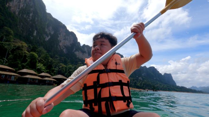 一名身穿救生衣的亚洲男子在湖中学习皮划艇