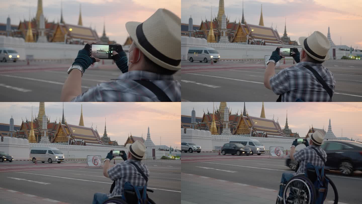 曼谷概念轮椅旅游地标。坐轮椅的游客使用手机拍摄大皇宫（Wat Phra Kaew），并使用平板电脑。