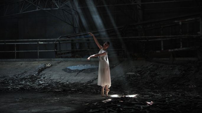年轻女子美丽的芭蕾舞演员在黑暗中与光明共舞。放大