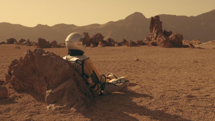 火星上的孤独。女宇航员探索锈色沙漠。坐在岩石上