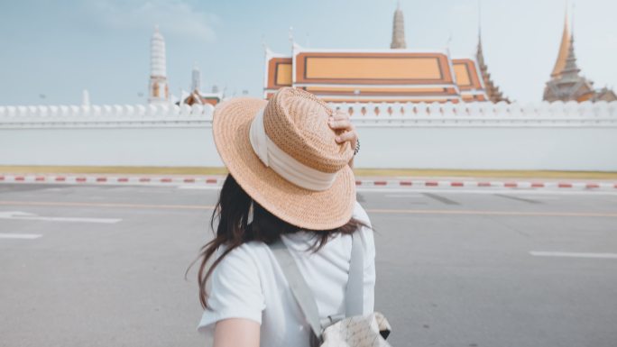 在曼谷的Wat Phra Kaeo，一位快乐的亚洲年轻女子牵着男友的手旅行