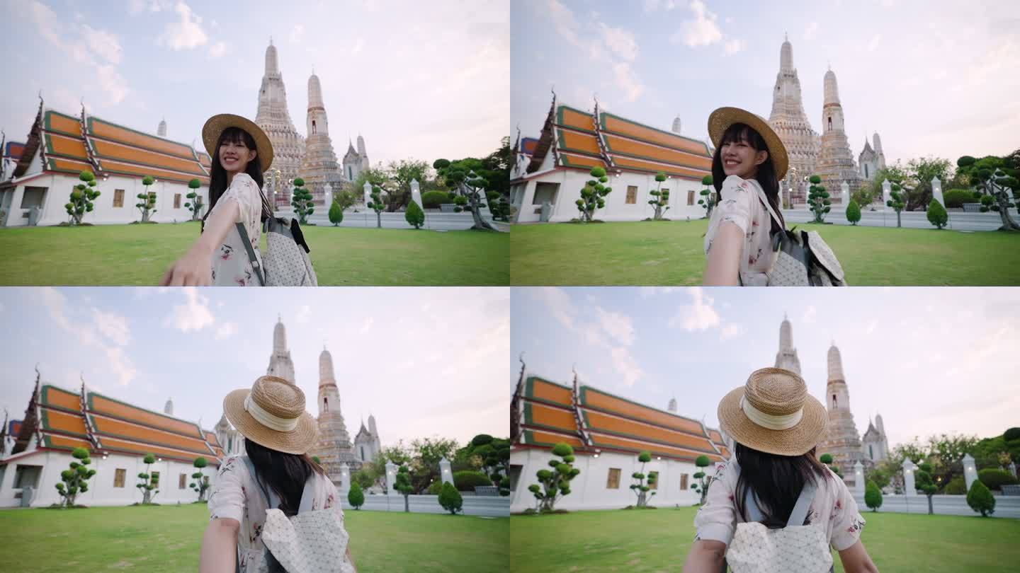 在曼谷Wat Arun，一位快乐的亚洲年轻女子牵着男友的手旅行