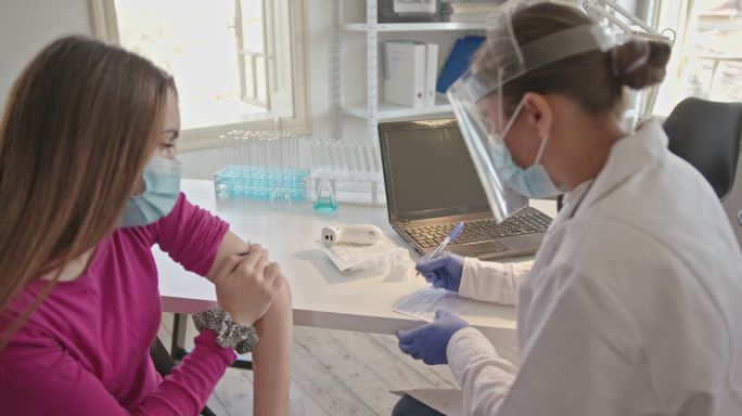 在疫苗接种中心向青少年发放新冠肺炎疫苗接种证书。