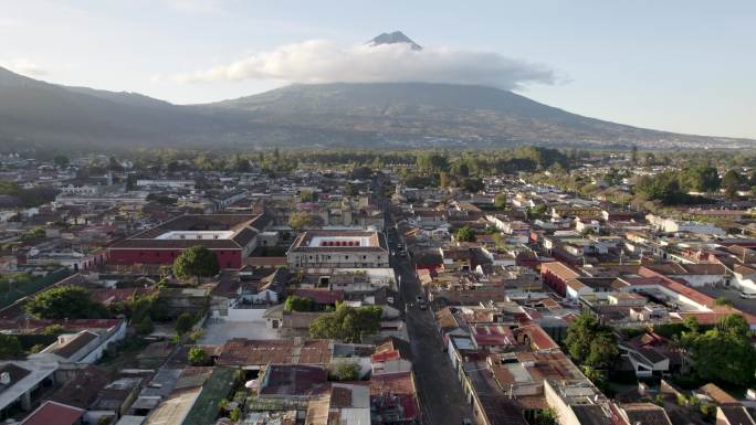 在阳光明媚的日子里，安提瓜危地马拉静止的阿瓜火山、鹅卵石街道和屋顶的景色