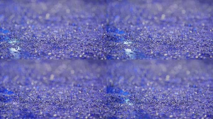 当光源在反射中闪烁时，许多小的铝金属屑在充满活力的蓝色表面上缓慢移动