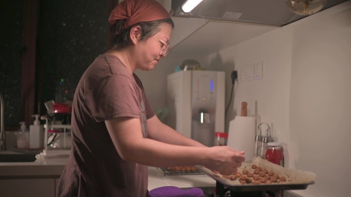 在家厨房里捡起烤花生饼干的亚裔中国中年妇女