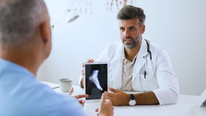 男医生给病人看脚的X光照片。