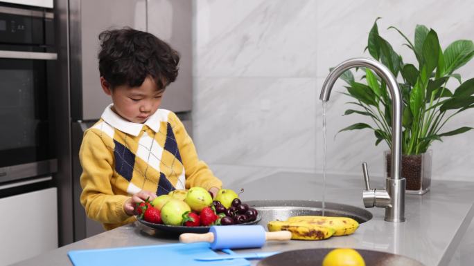 小男孩正在厨房里洗水果