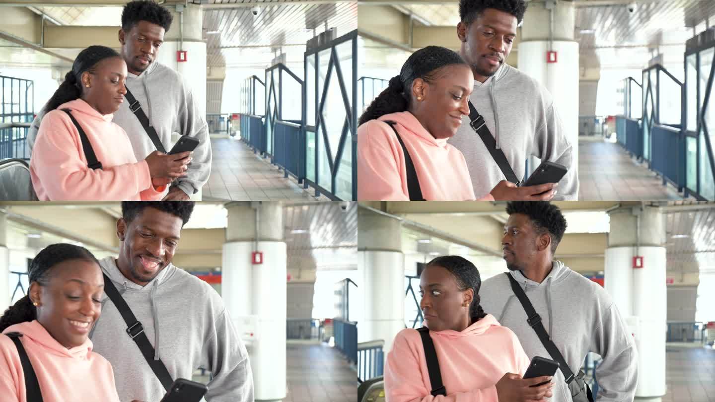 火车站台上的一对黑人夫妇看着手机