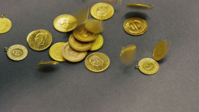 金币。珠宝商把金币掉在托盘上。一个真实金币的慢镜头。
