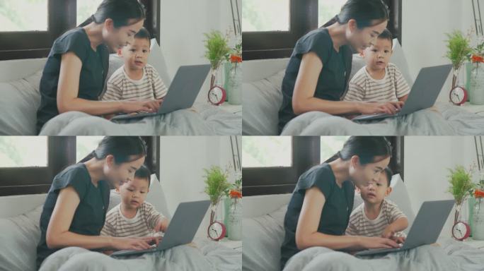 母亲和她的小男孩玩电脑的镜头。