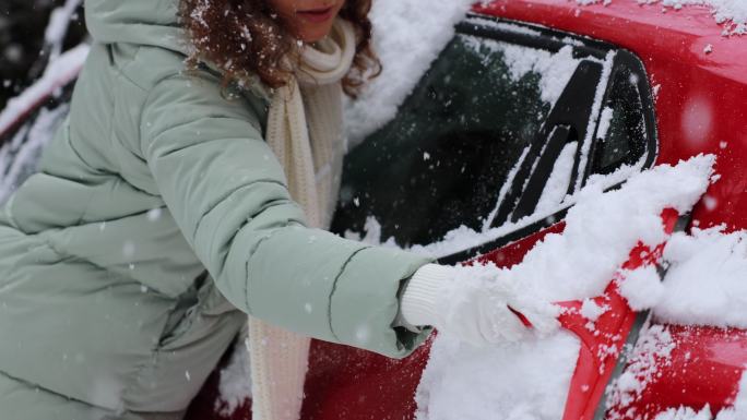 一位年轻女子正在清理汽车上的积雪