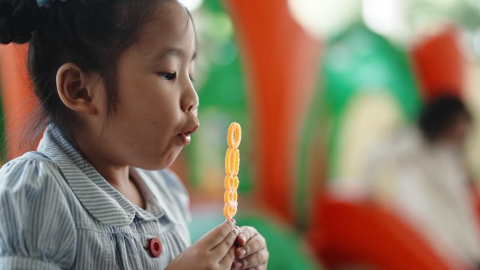 一个亚裔中国女孩放学后在操场上和同学一起吹泡泡