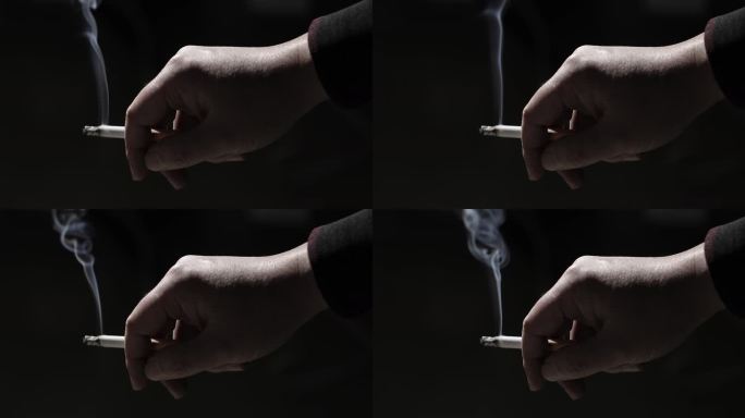 手指夹着燃烧的香烟特写