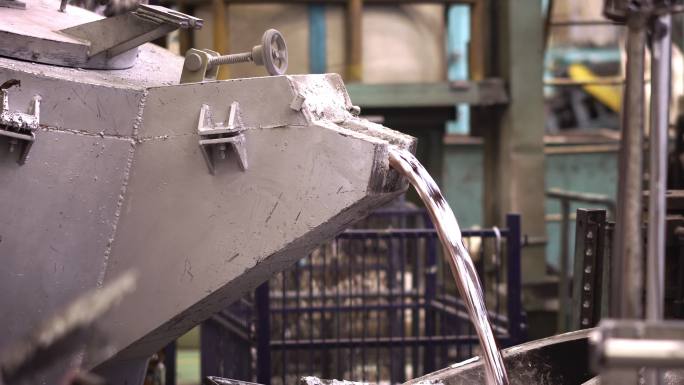铝熔炼，操作员努力将钢包中的熔融金属敲入保温炉压铸机