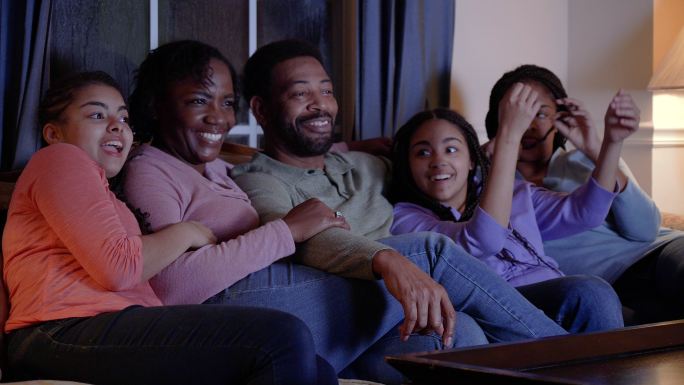 有三个女儿看电视的非裔美国人家庭