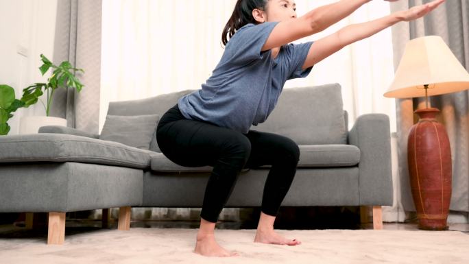 一个女人蹲在你家的客厅里。在家锻炼。