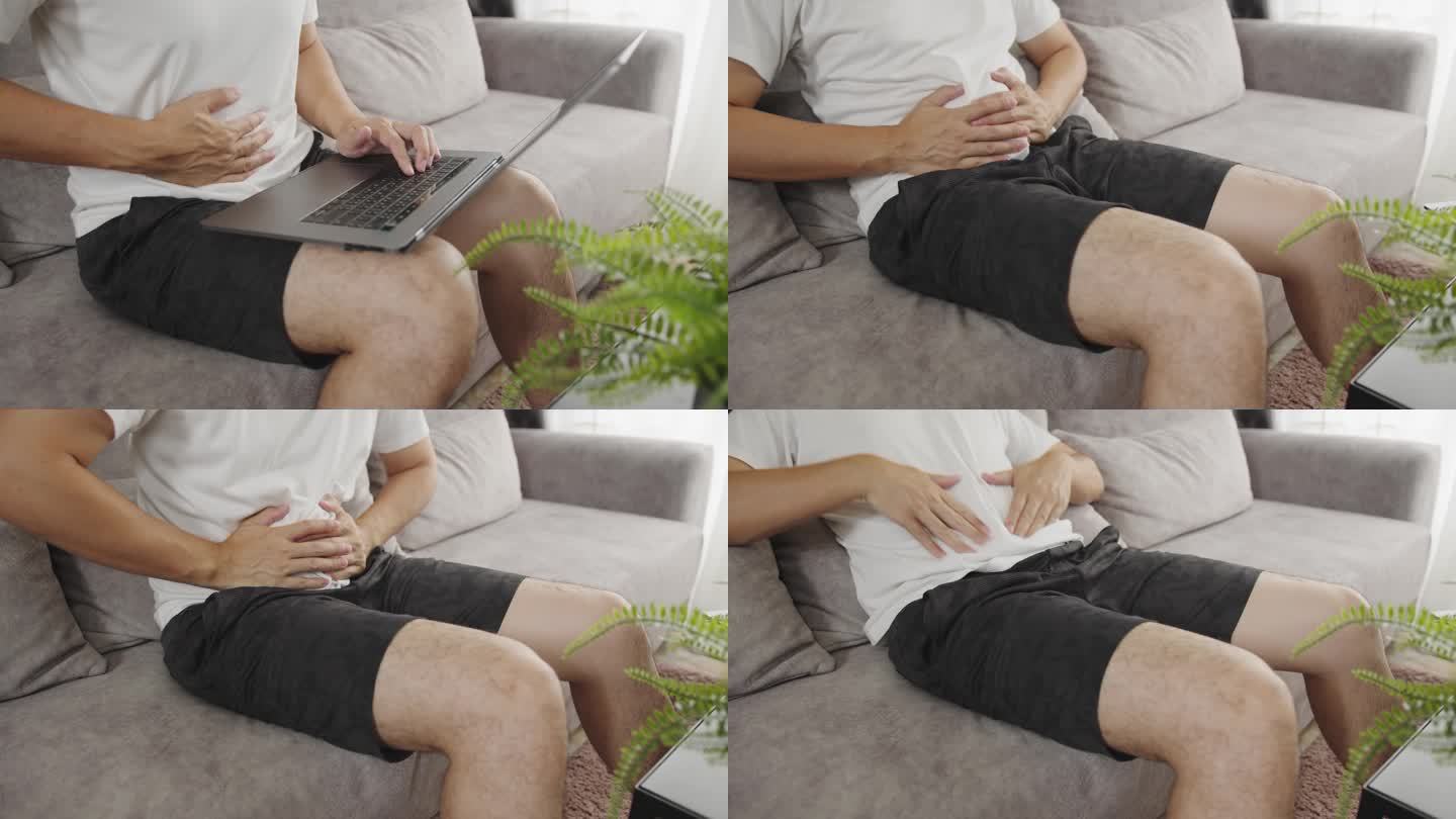 一名亚洲男子躺在沙发上，在家中胃痛