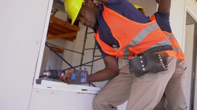 美国黑人建筑工人在木结构房屋施工中安装窗户