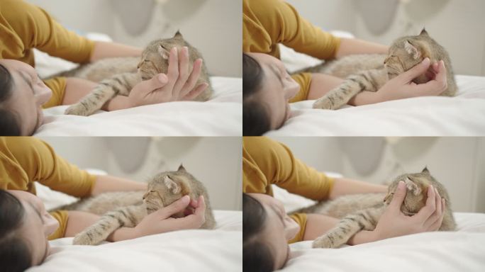 一只可爱的猫睡在亚洲女主人的怀里，躺在家里的床上。