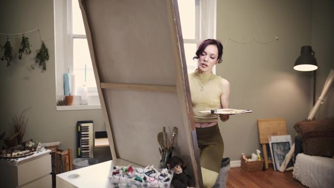 年轻的白人女艺术家在画室里画画