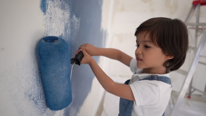 可爱的小男孩在家里用油漆滚筒画画，面带微笑
