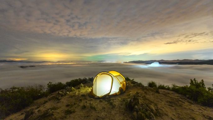山顶照明帐篷的锁定延时拍摄，夜间有雾和银河覆盖天空