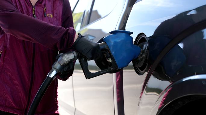 新冠肺炎期间，一名妇女戴着防护手套在加油站给汽车加油