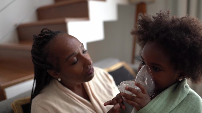母亲帮助女儿在吸入疗法中使用雾化器