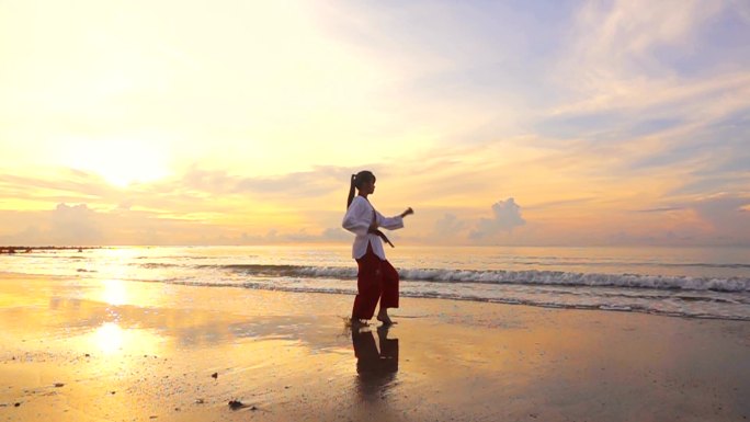 高清超级慢动作：日落时分，年轻女性在户外海滩练习武术