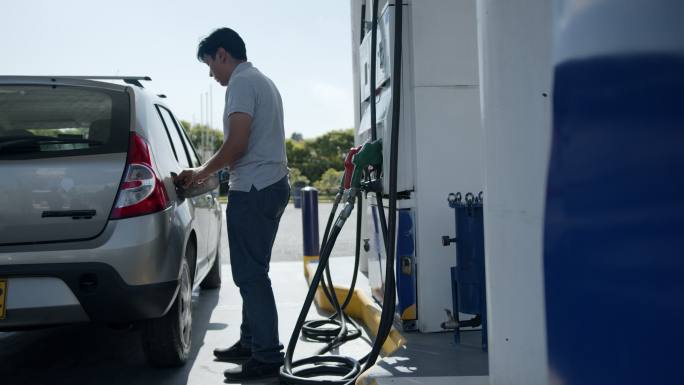 一名拉丁美洲男子在自助加油站为油箱加油