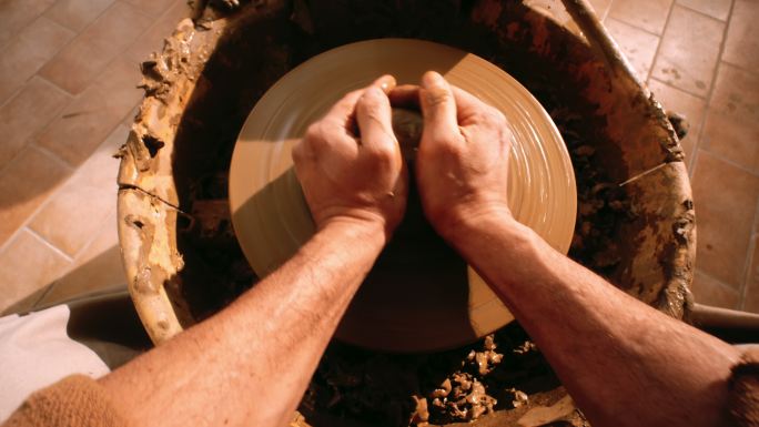 POV男陶工将粘土放在陶工的轮子上
