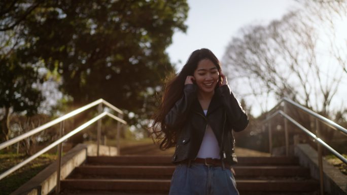 年轻女子一边听音乐一边在公园里快乐地散步