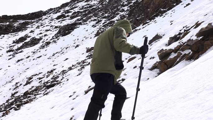 爬雪山 男子穿冲锋衣爬雪山 拄拐棍爬雪山