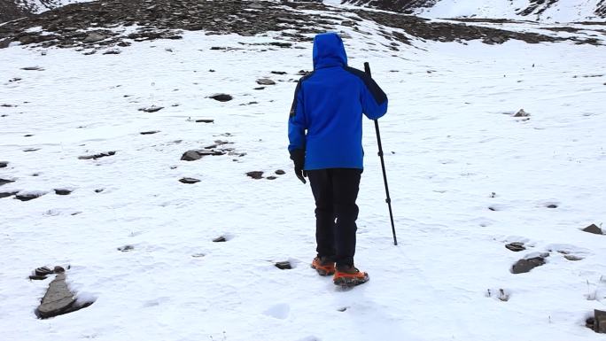 男子穿冲锋衣爬雪山 拄拐棍爬雪山 登山