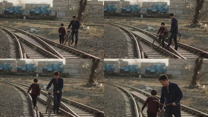 推自行车的父亲带着男孩走过铁路