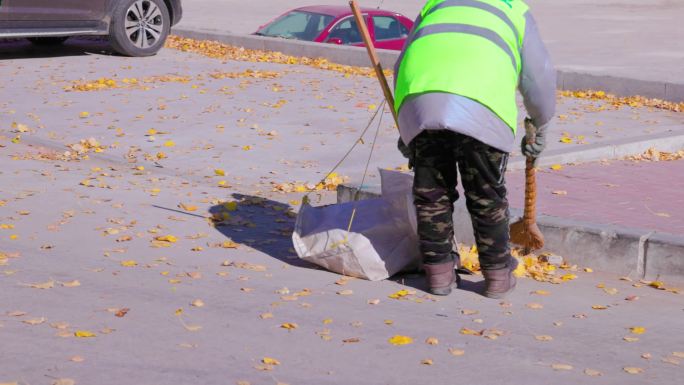 环卫工正在清理马路上的树叶
