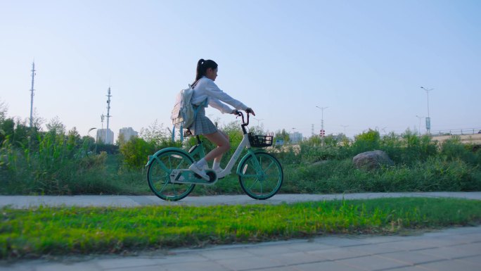 户外 朝阳骑共享单车的女孩早晨快乐骑行