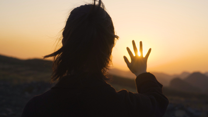 唯美女生山顶眺望夕阳伸手触摸阳光风吹发丝