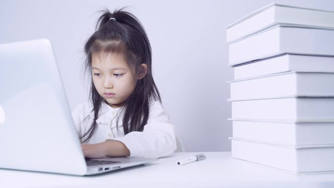 在书桌上使用笔记本电脑的小女孩