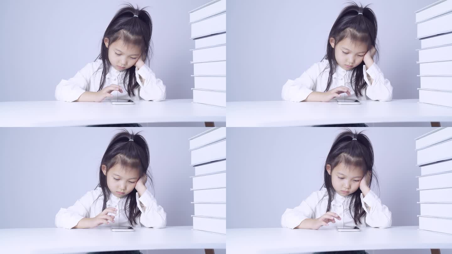 在书桌上使用手机的小女孩