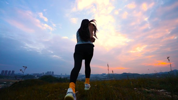 时尚女孩山顶向着太阳奔跑黄昏登山奔跑庆祝