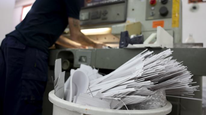 无法识别的工人在印刷厂，在CNC切割机上切割纸张束