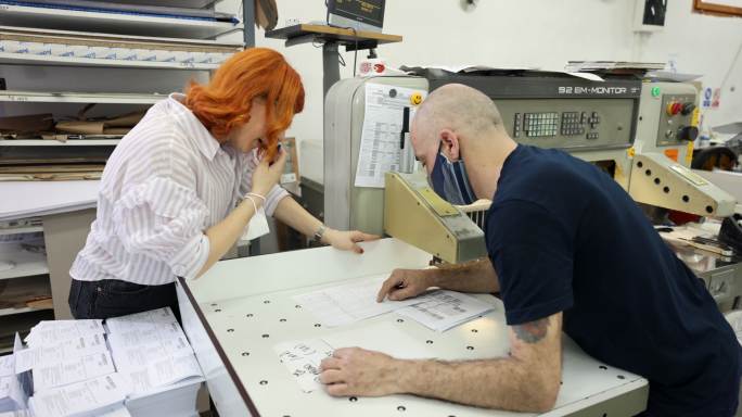 白人男女同事在印刷厂组织工作日程