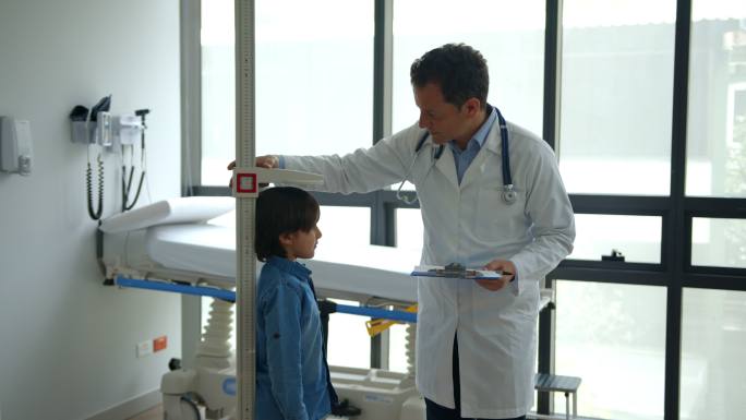 友好的儿科医生一边给他9岁的病人打个招呼，一边给他打个招呼一边微笑