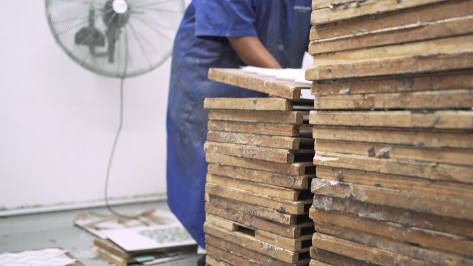 工人在工厂里从六角形瓷砖上拆除网格